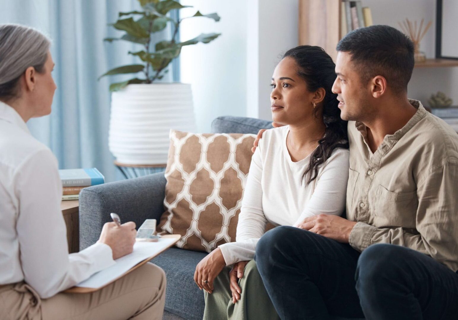 A man and woman sitting on the couch looking at each other.