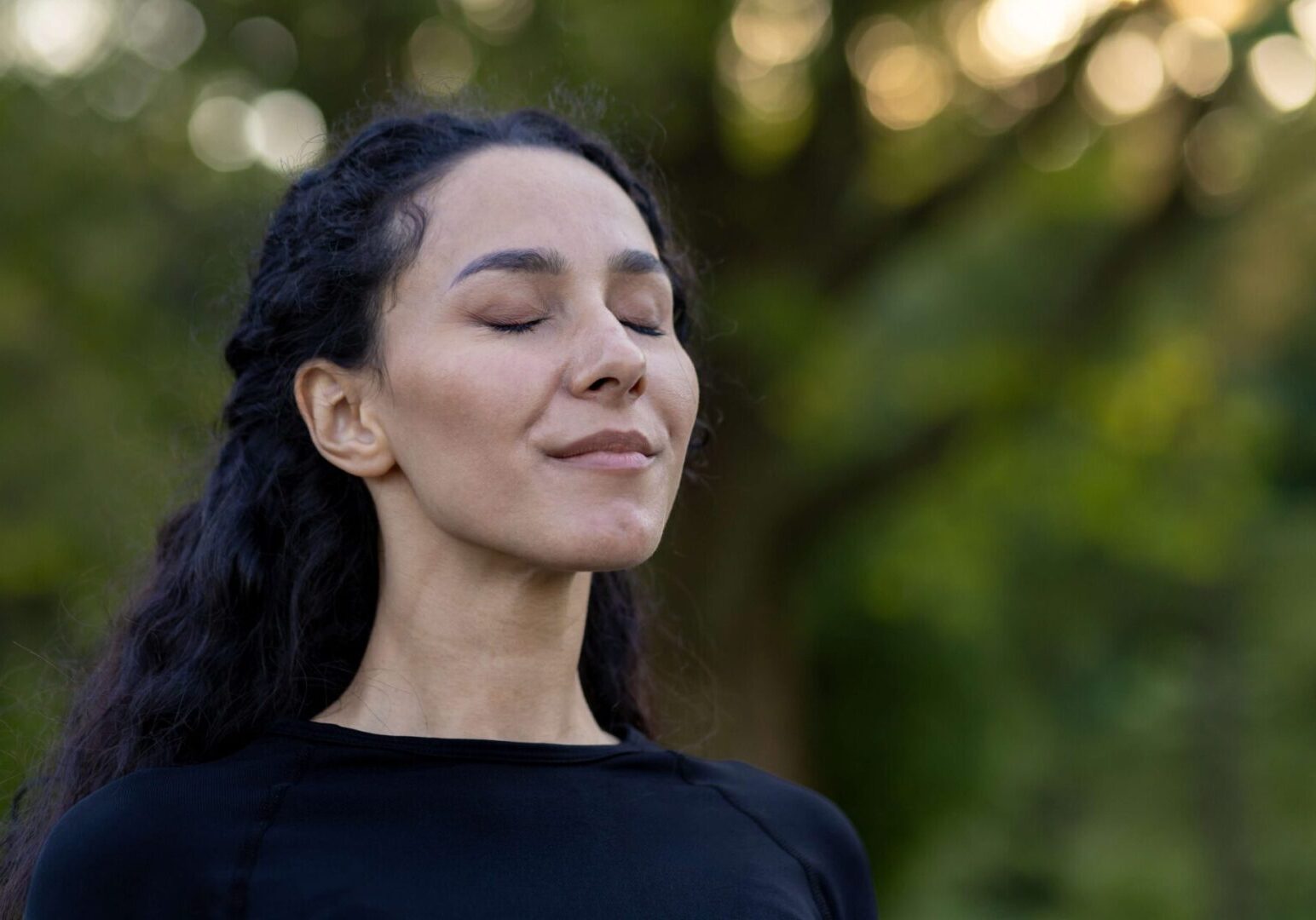 A woman with her eyes closed and hands in the air.